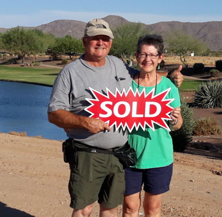 Older couple holding a sold sign regarding the sale or purchase of a property in Surprise, AZ